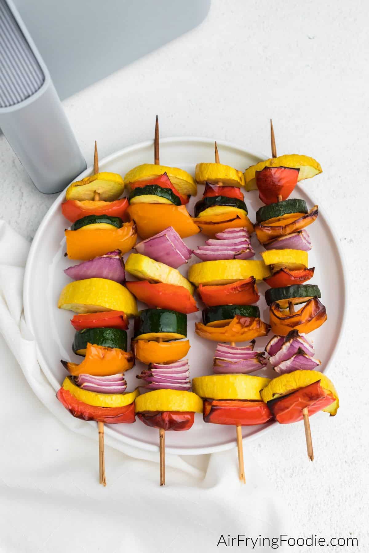 Colorful grilled vegetable skewers with peppers, zucchini, and onions on wooden sticks.